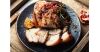 Herb-crusted pork belly roast sliced with pomegranate seeds, garlic rosemary